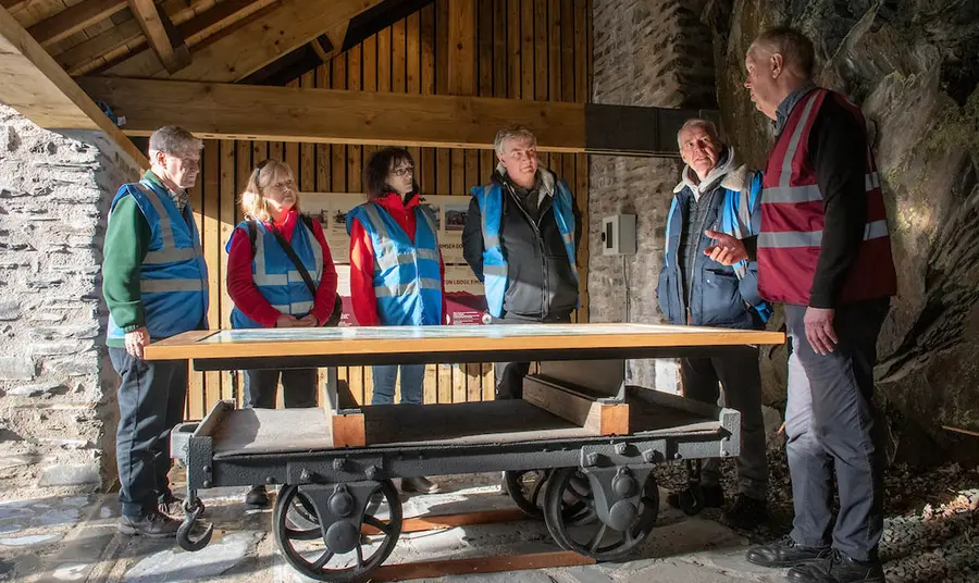 A group of people in high-vis standing around a table converted from an old railway wagon