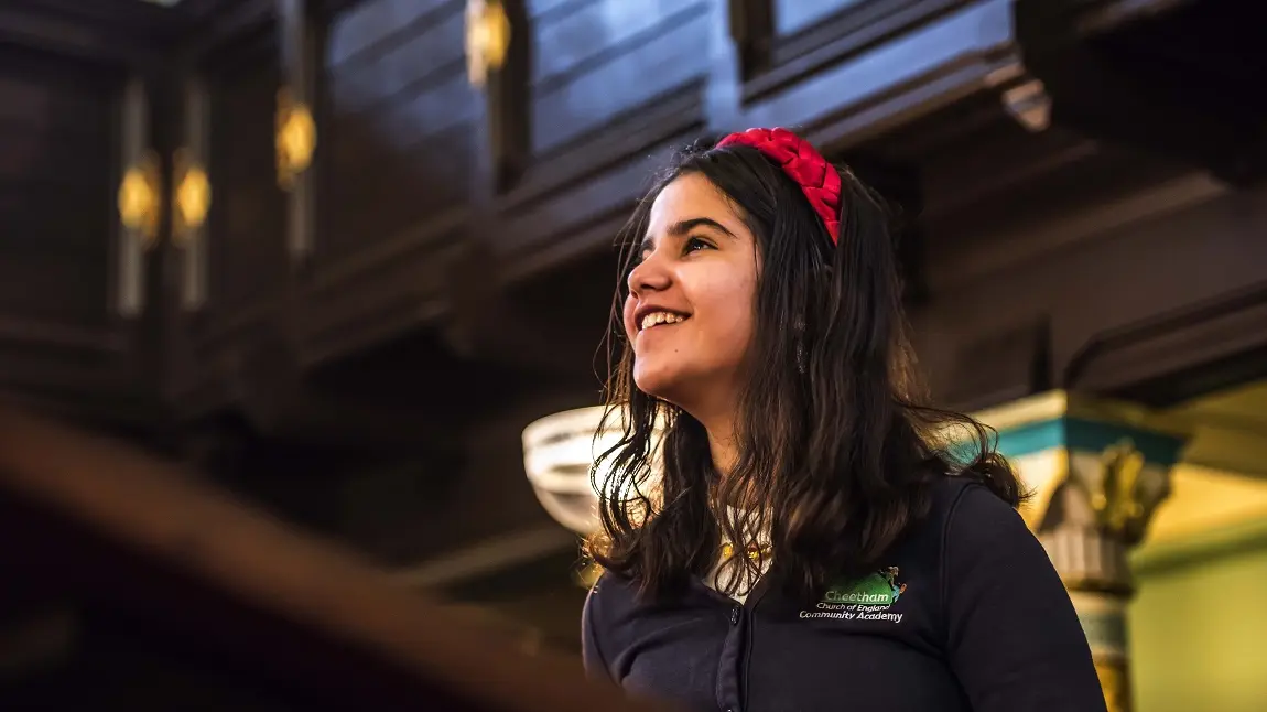 Schools Workshop in the Synagogue, image by Chris Payne.JPG A young child in a school uniform looking up and smiling inside a synagogue
