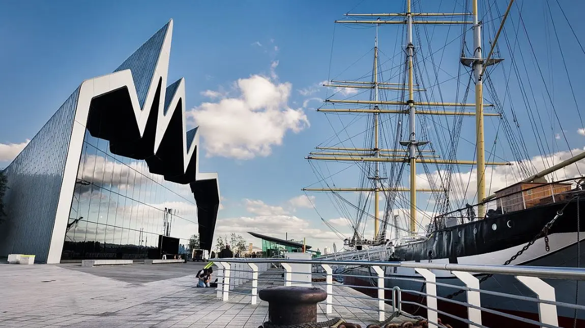 A view of the facade of the Riverside Museum in Glasgow, opposite a docked tall ship in the Clyde.
